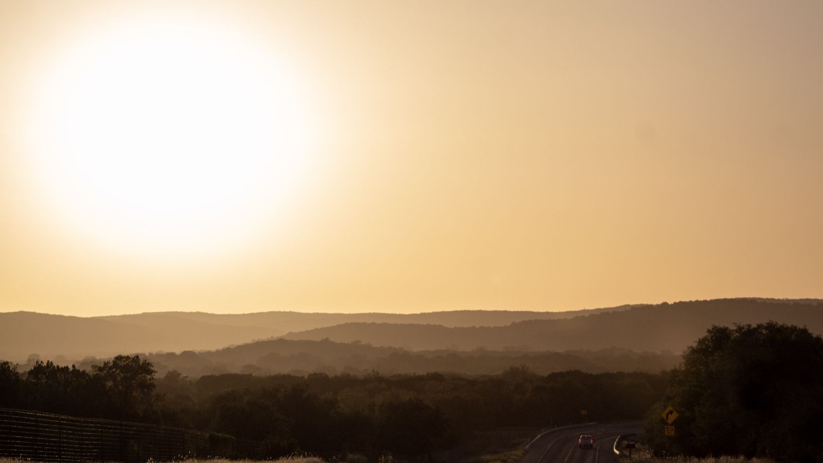 A big low sun over hazy rolling hills, soft golden light.