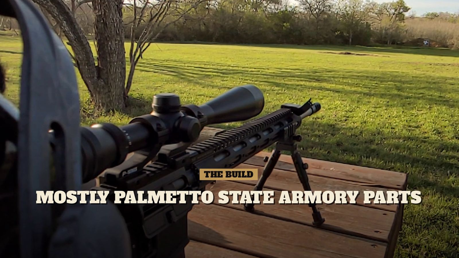 My home-built rifle with a 4-12x scope and bull barrel, resting on a bipod on a wooden table, looking out over a grassy field.
